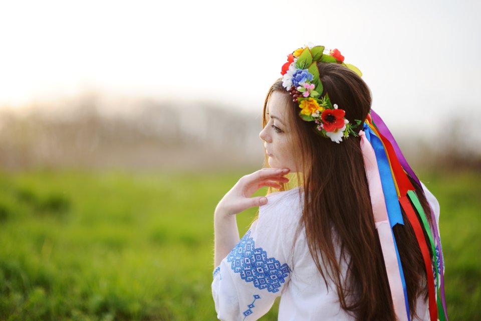 beautiful young girl in a wreath from flowers on head on the background of nature in spring